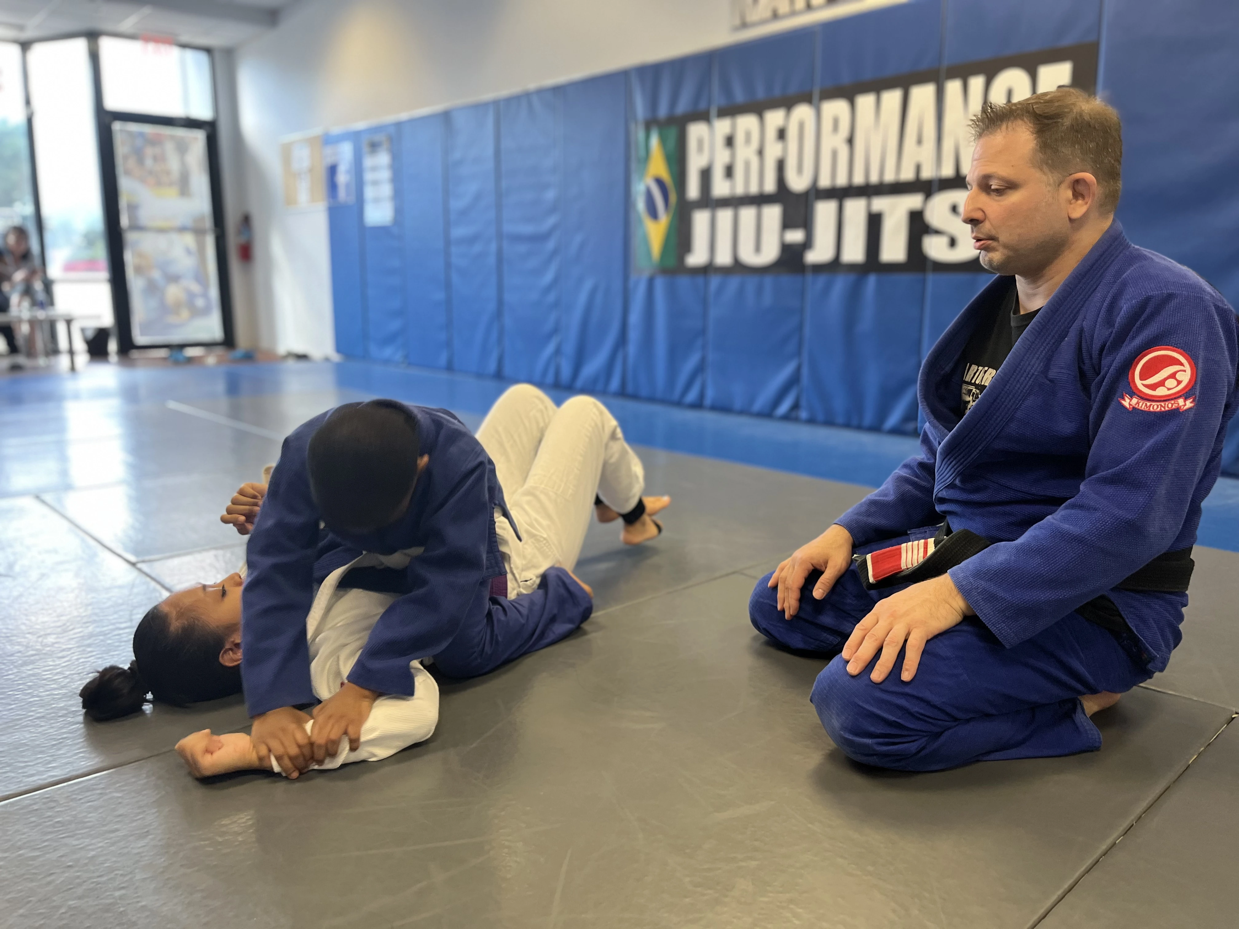 Instructor coaching two kids during a Brazilian Jiu-Jitsu class in Fair Lawn, NJ